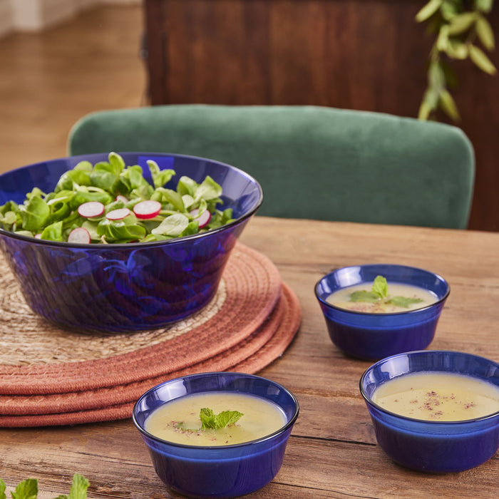 Duralex Lys. A stylish sapphire blue salad bowl with a flat base and edges that curve slightly outwards with three matching soup bowls. Un bol à salade chic bleu saphir avec une base plate et des bords qui s'incurvent légèrement vers l'extérieur, accompagné de trois bols à soupe assortis.